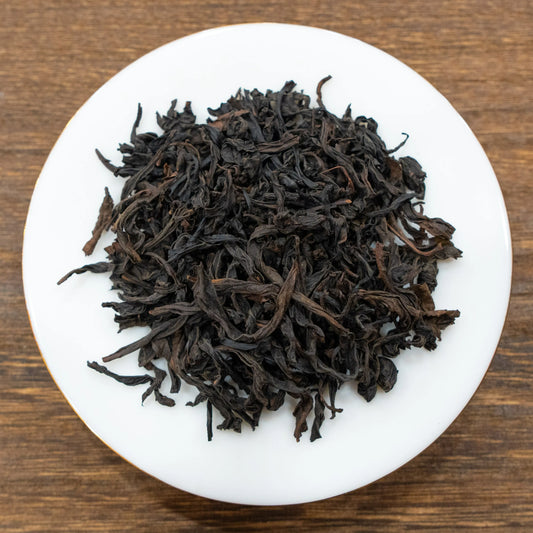 Rooteas dry iron arhat rock tea leaves on a white plate with a wooden background