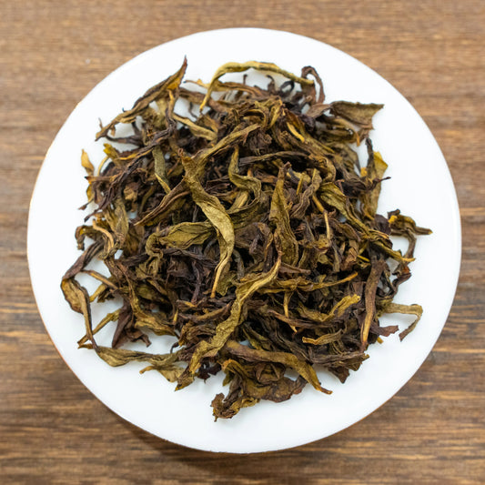 Rooteas dry white cockscomb rock tea leaves on a white plate with a wooden background