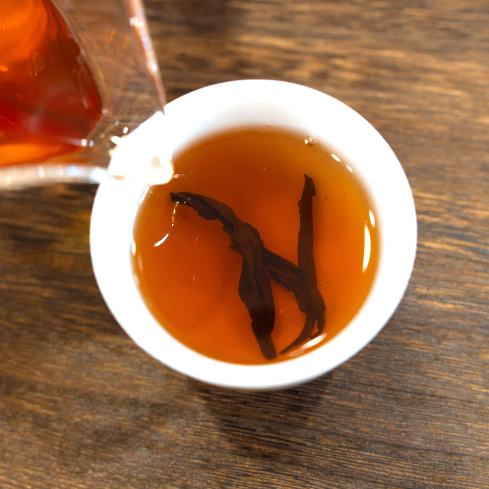 Brewed halfway up the sky rock tea of rooteas being poured into a white cup on a wooden surface