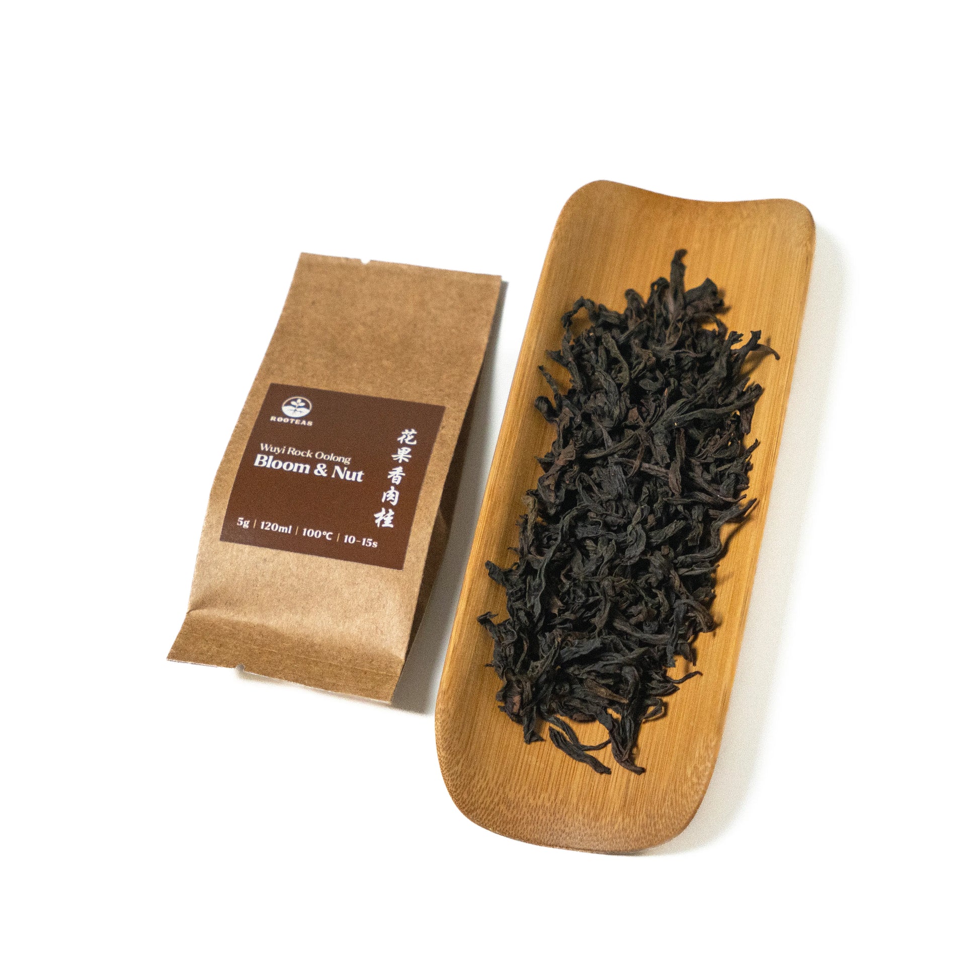 Dried rock oolong tea leaves on a wooden board with a brown packaging sleeve on a white background