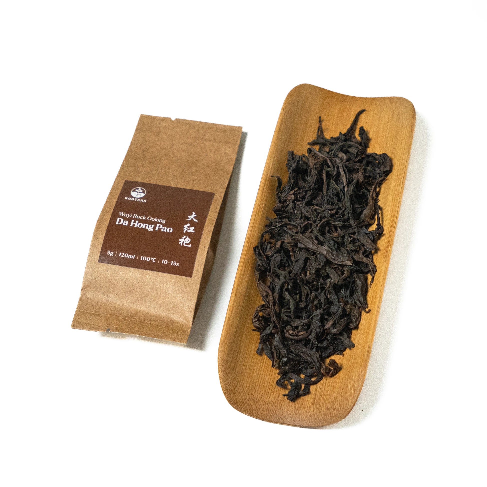 Dried rock oolong tea leaves on a wooden board with a brown packaging sleeve on a white background