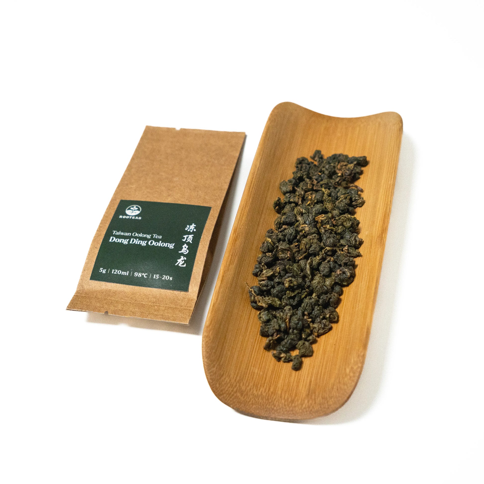 Tea package and a wooden tray with tea leaves on a white background