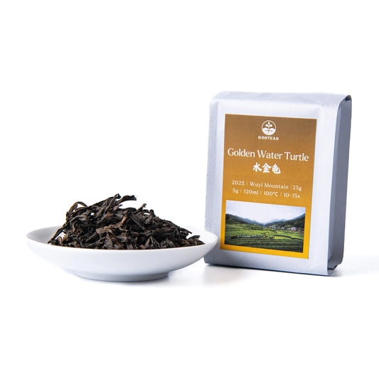 White bowl with rooteas dry golden water turtle rock tea next to its packaging on a white background