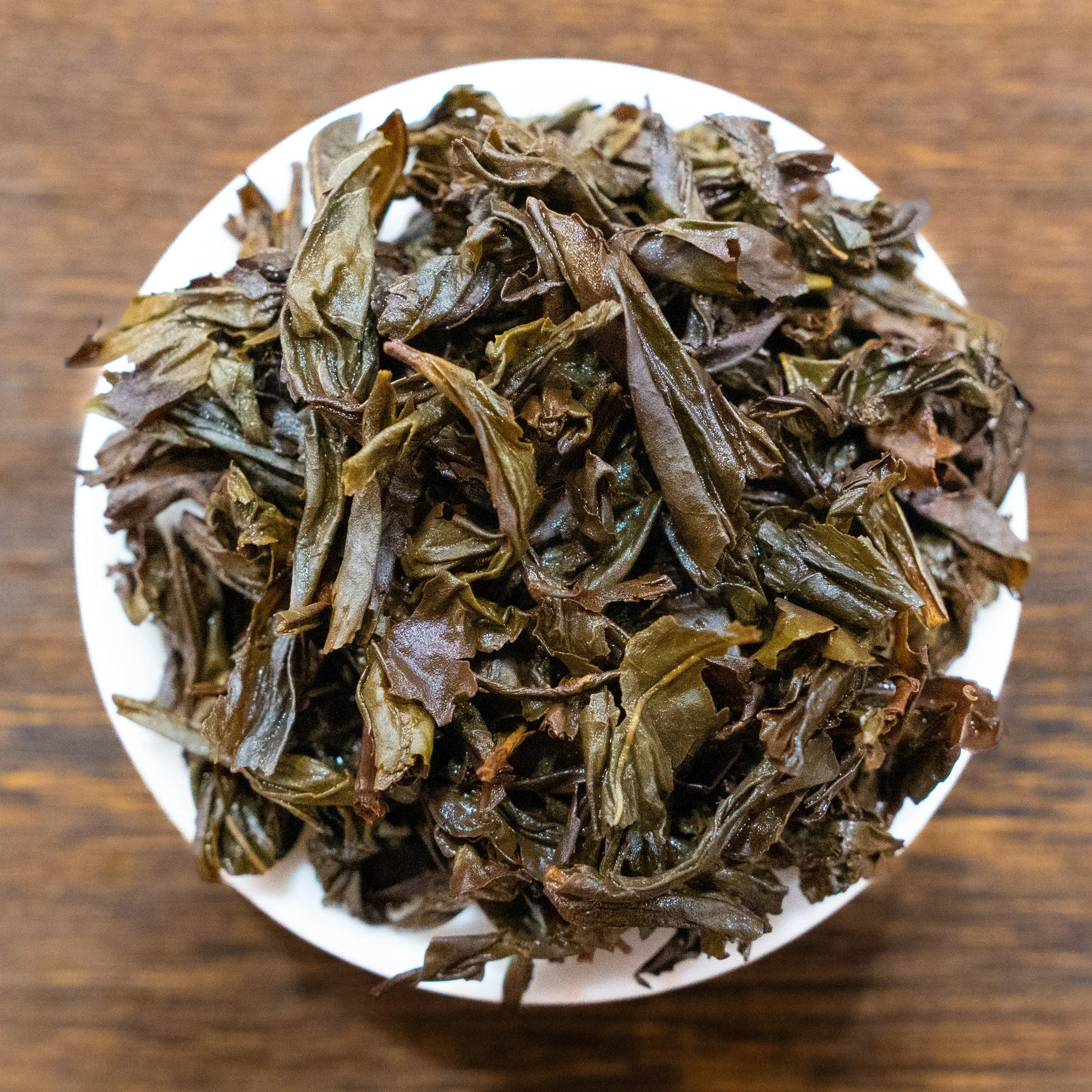 Rooteas brewed halfway up the sky rock tea leaves on a white plate with a wooden background