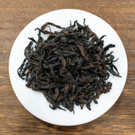 Rooteas dry halfway up the sky rock tea leaves on a white plate with a wooden background
