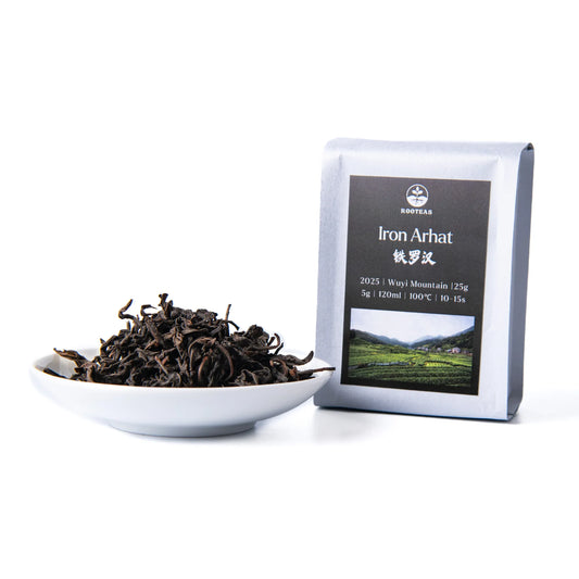 White bowl with rooteas dry iron arhat rock tea next to its packaging on a white background