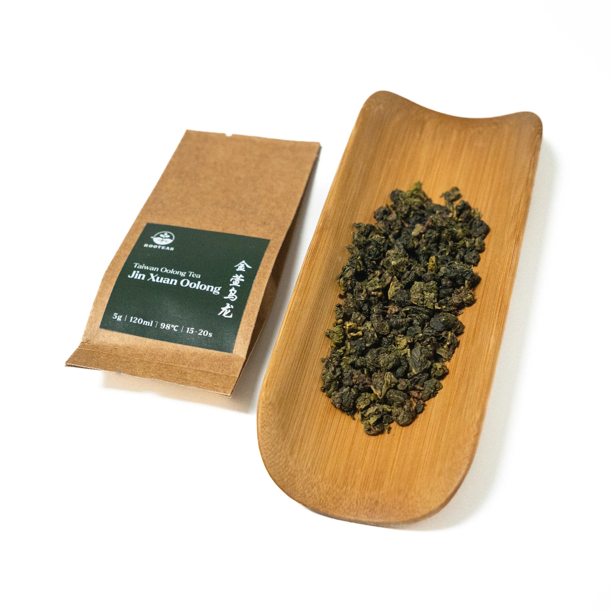 Tea package and a wooden tray with tea leaves on a white background