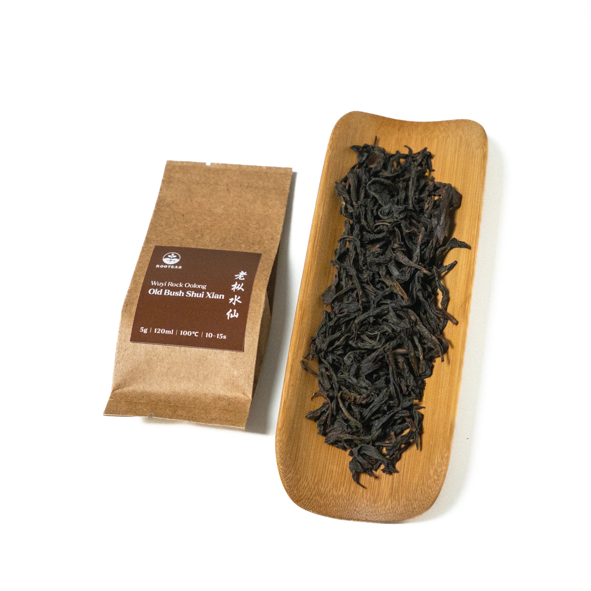 Dried rock oolong tea leaves on a wooden board with a brown packaging sleeve on a white background