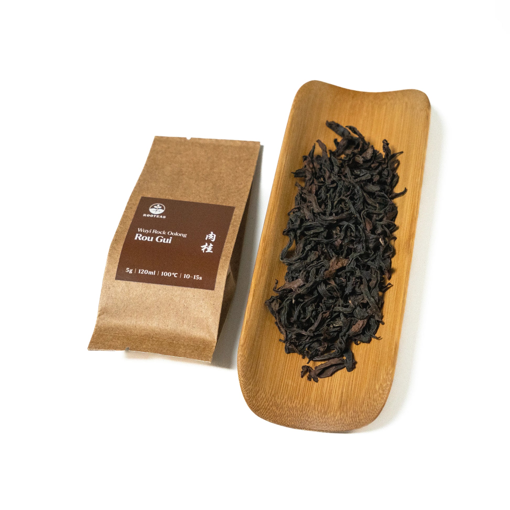 Dried rock oolong tea leaves on a wooden board with a brown packaging sleeve on a white background