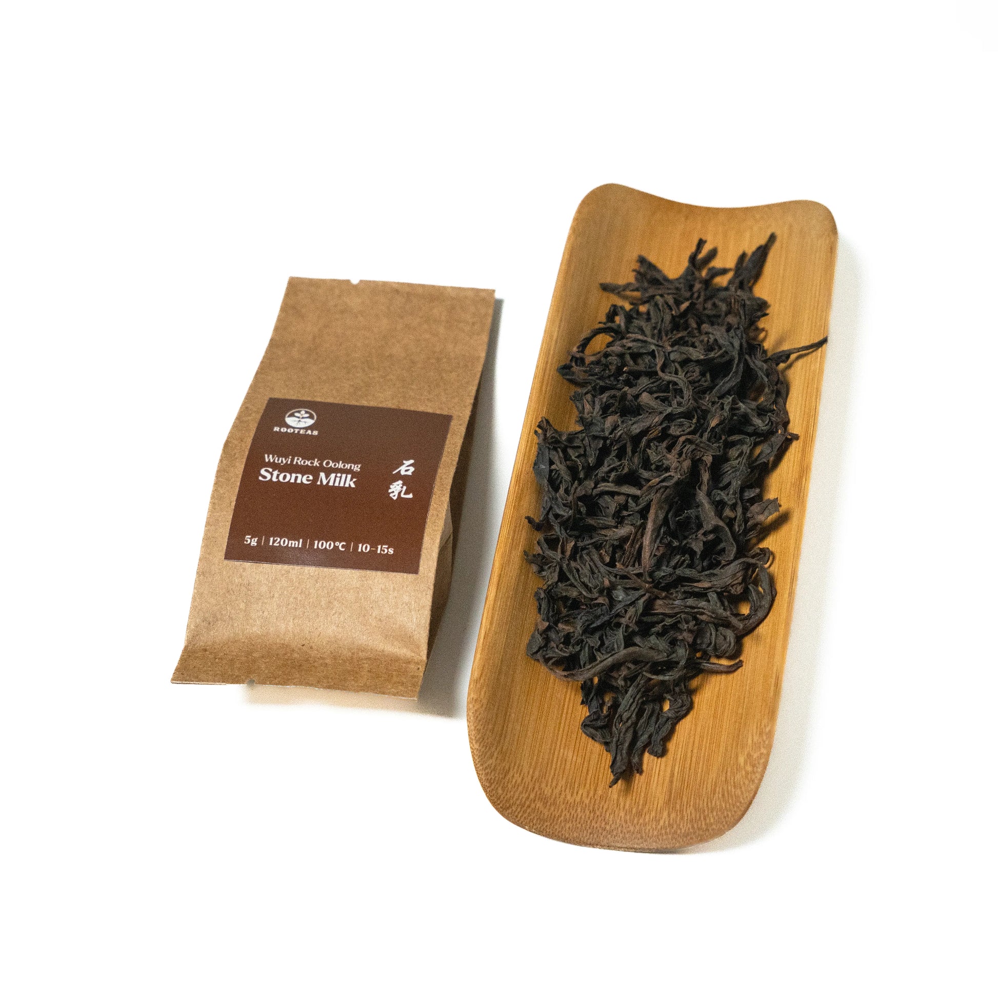 Dried rock oolong tea leaves on a wooden board with a brown packaging sleeve on a white background