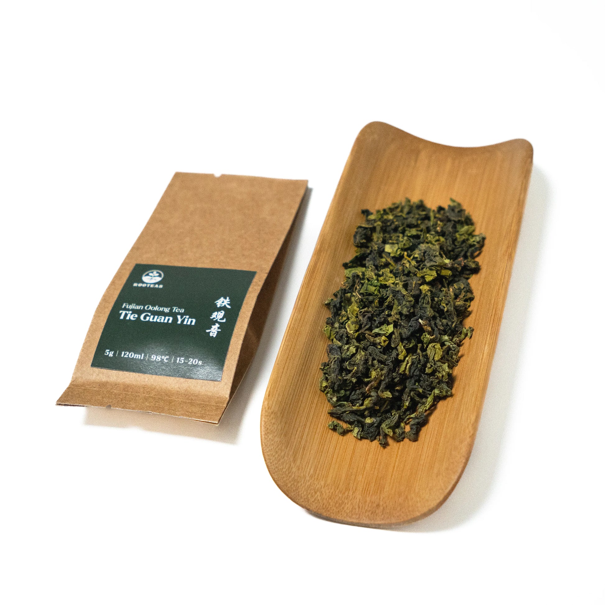 Tea package and a wooden tray with tea leaves on a white background