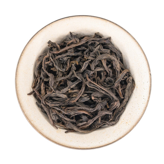 Dry wu san di lao cong shui xian tea leaves in a white gaiwan on a white background